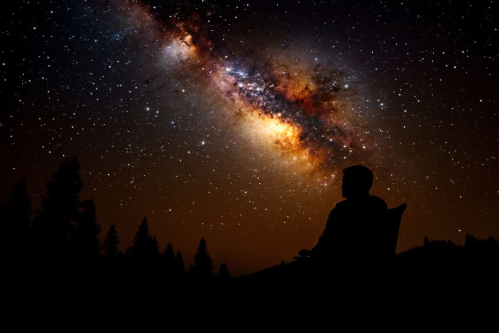 A realistic serene image demonstrating how to start stargazing showing a person looking up at the brilliant Milky Way from a simple camping chair on a clear night